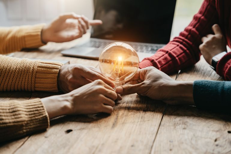 Personnes reliées par une ampoule scintillante symbolisant l'échange et la connexion 